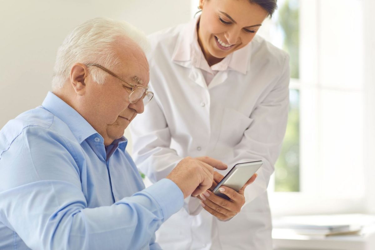 Ärztin zeigt älterem Patienten Ergebnisse auf einem Tablet