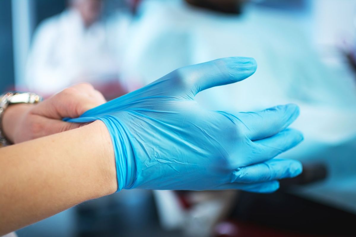 Hände ziehen medizinische Handschuhe an