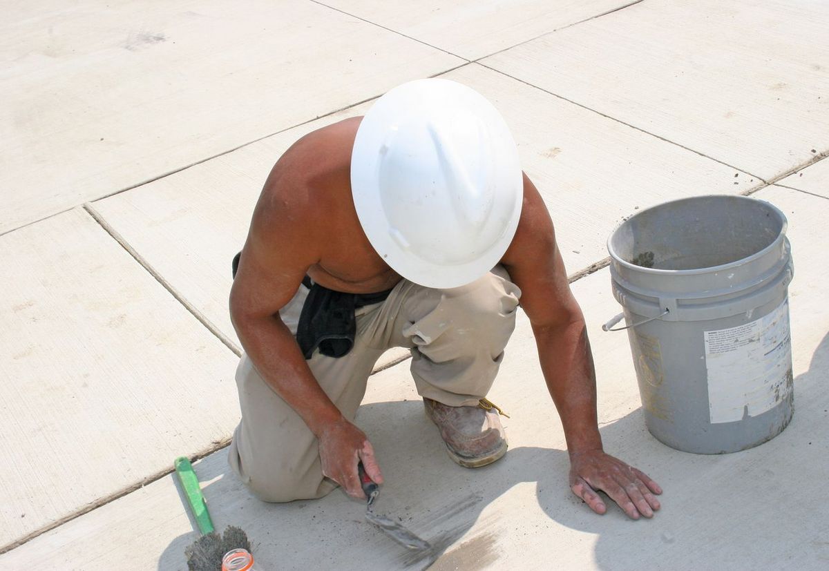 Arbeiter verlegt Boden mit nacktem Oberkörper an der Sonne
