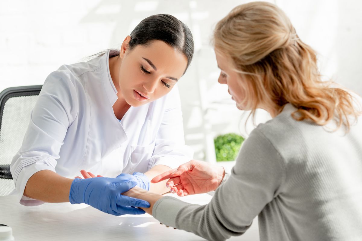 Ärztin untersucht Hand einer Patientin